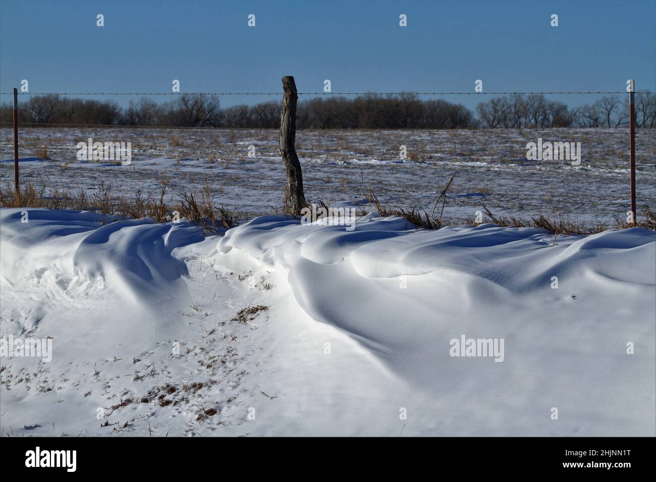 Snow Drift with a fence and field out in the country Stock Photo