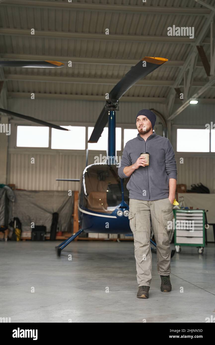 Bearded male walking in garage with copter Stock Photo