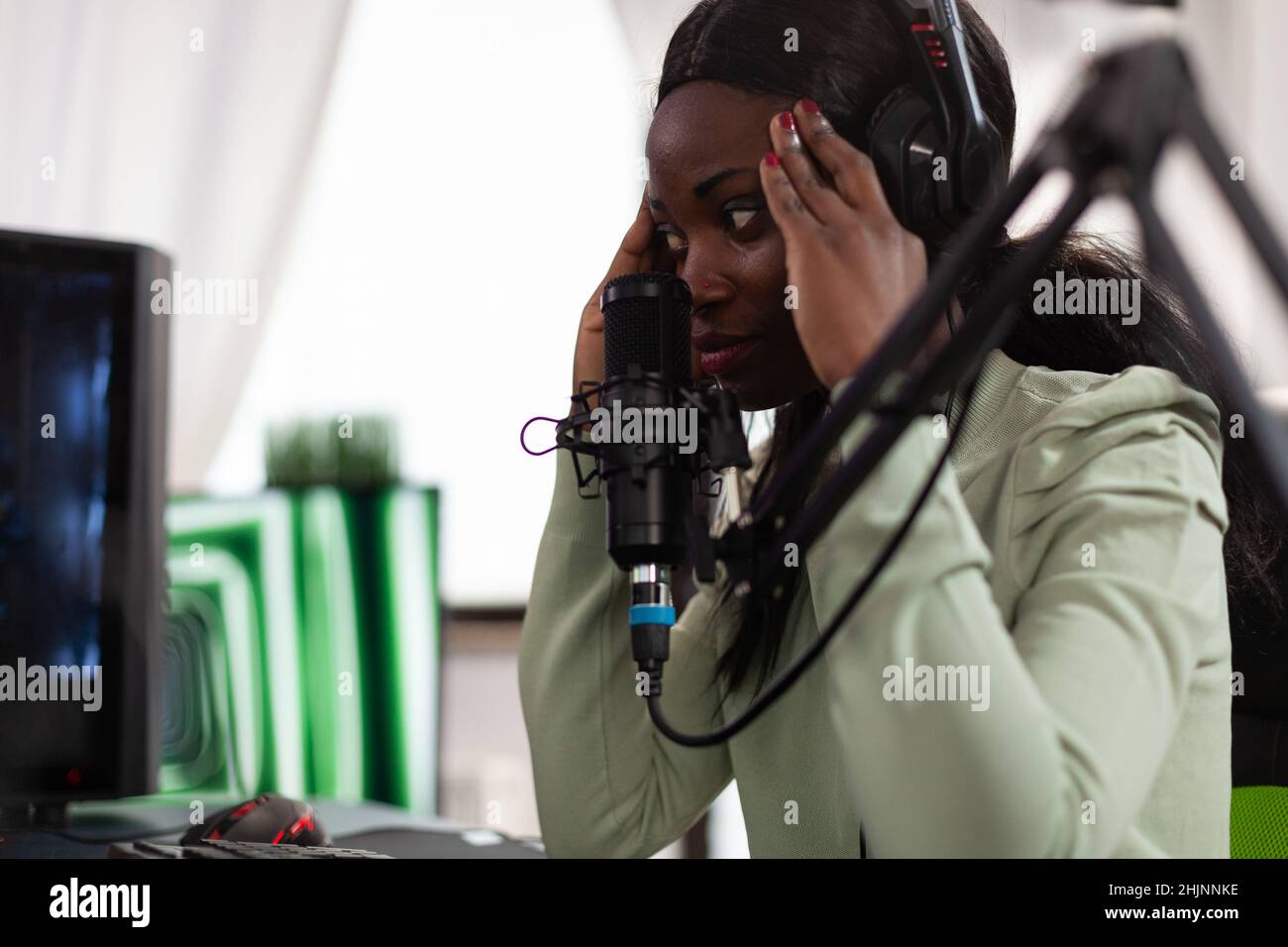 Upset sad pro gamer playing space shooter video games using RGB computer, gaming for online championship. Nervous woman player with headphones talking with remote player using live streaming Stock Photo