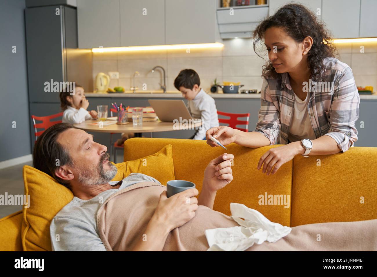 Wife checking her husband temperature on thermometer Stock Photo