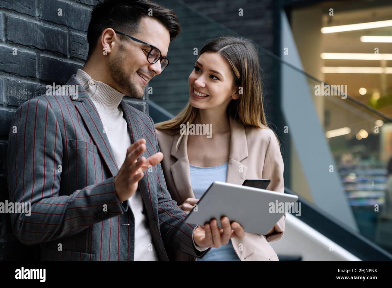 Successful young business people talking, working together in front of modern business building Stock Photo