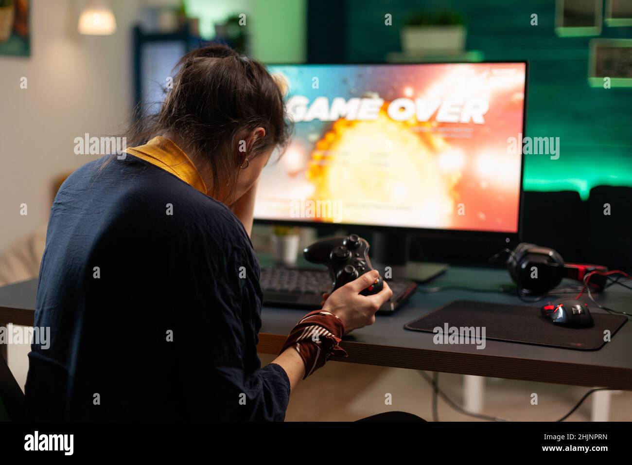 Angry woman playing online video games with joystick. Gamer using controller on computer to play internet games and losing. Disappointed person with electronic gaming equipment. Stock Photo