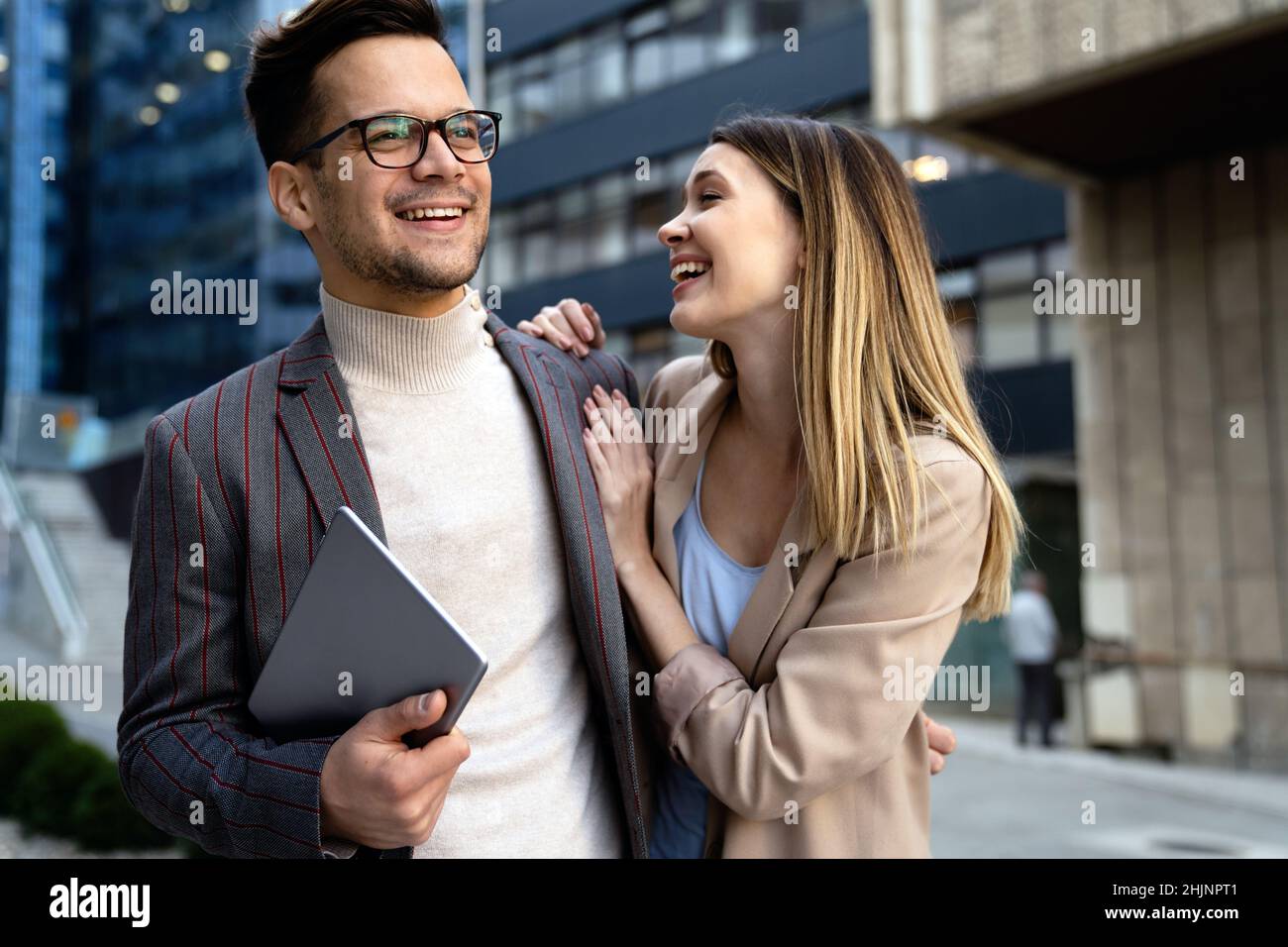 Successful young business people talking, working together in front of modern business building Stock Photo