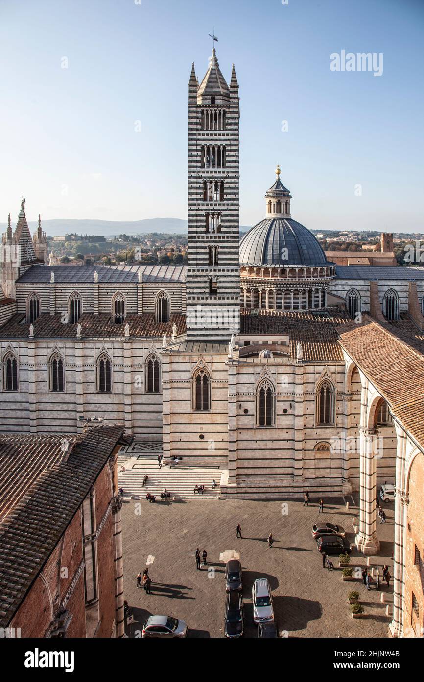 Elevated view of Siena Cathedral / Duomo di Siena, Tuscany, Italy. Piazza del duomo with cars and people; Campanile and cupola. Stock Photo