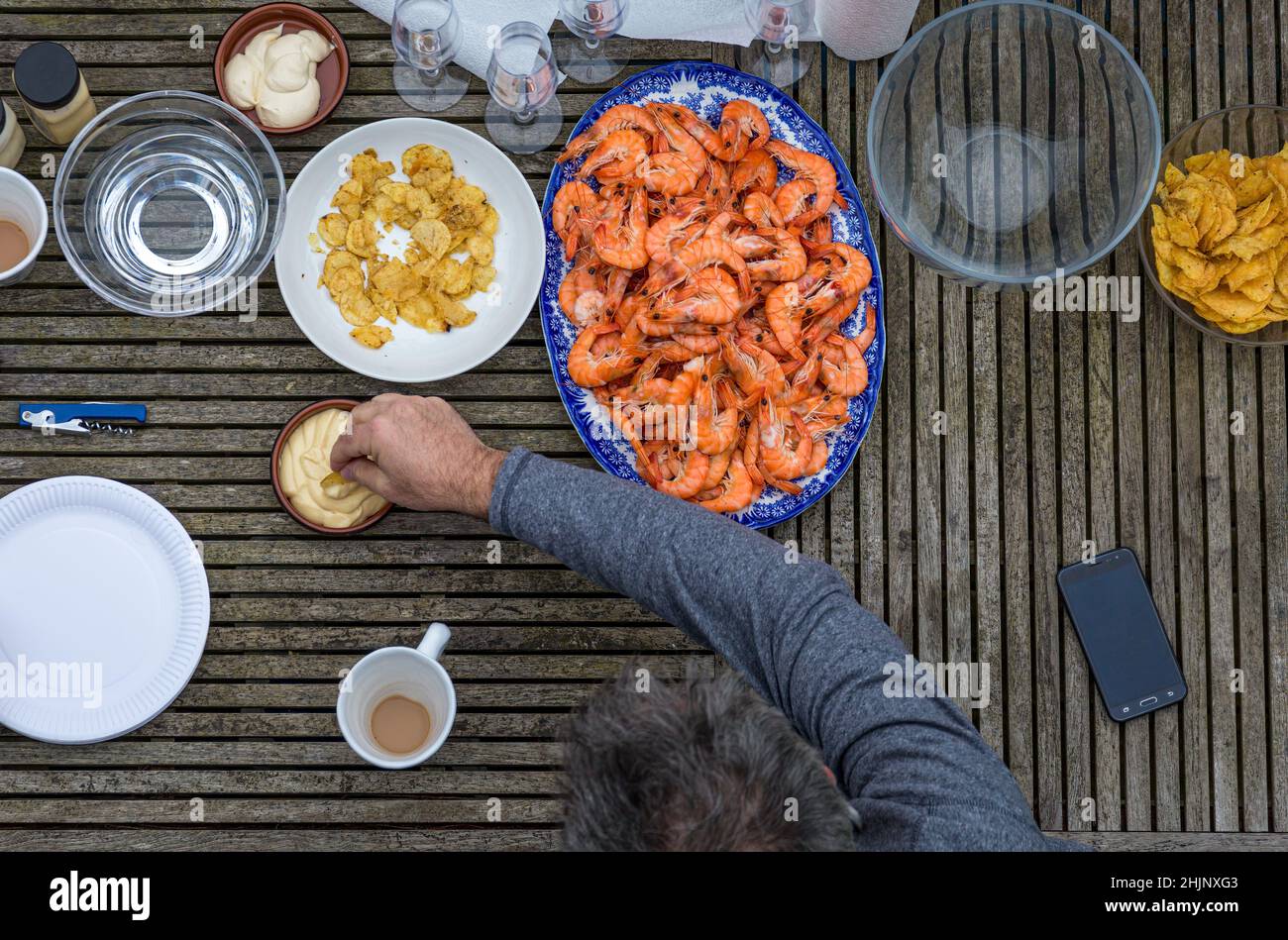 Overhead view of man enjoying prawns and mayonnaise in an outdoor setting Stock Photo