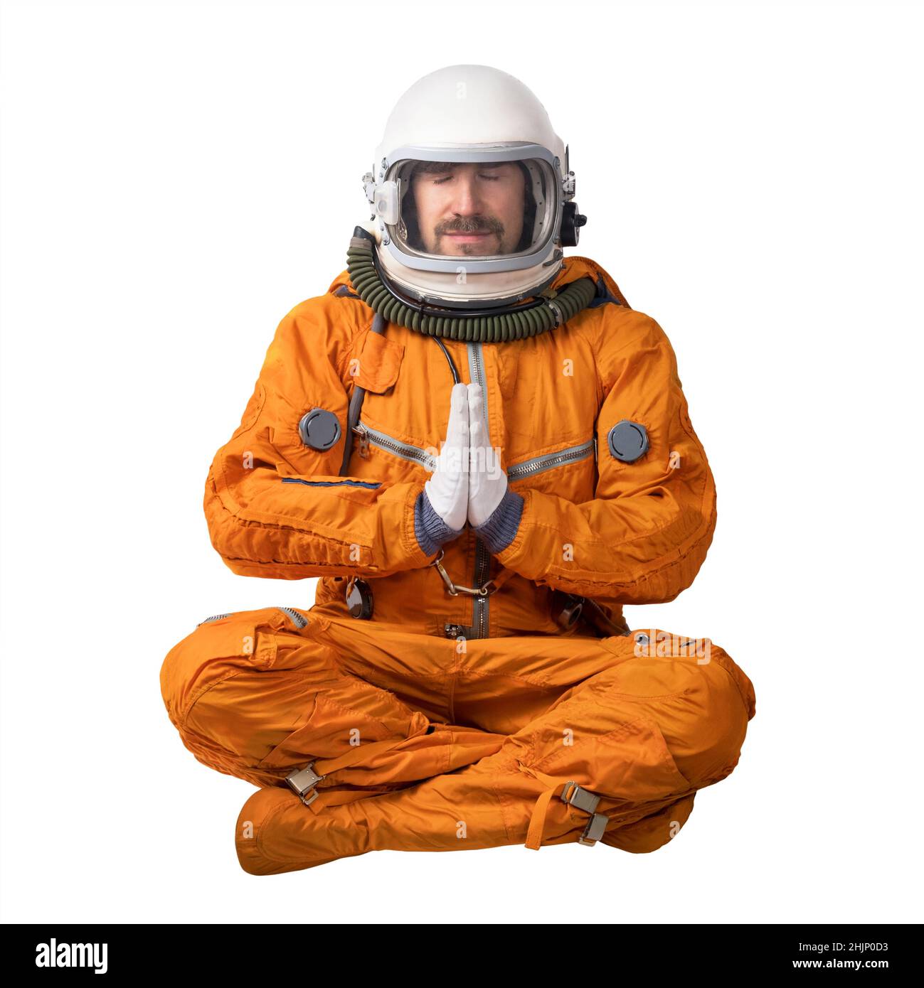 Astronaut wearing orange space suit and space helmet sitting in a lotus pose focused meditating putting his hands together in prayer gesture isolated Stock Photo