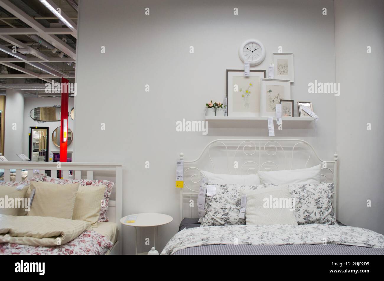 Moscow, Russia, September 2019: IKEA store bedroom interior: white color bed, linen, photo frames and wall clock. Furniture store. Stock Photo