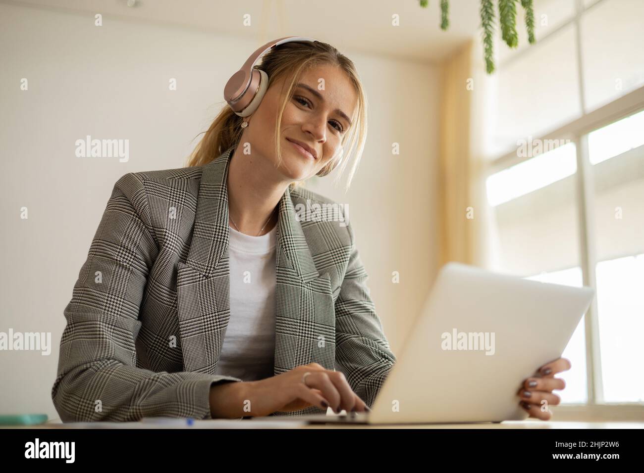 Young woman working at home with laptop and papers on desk and ...