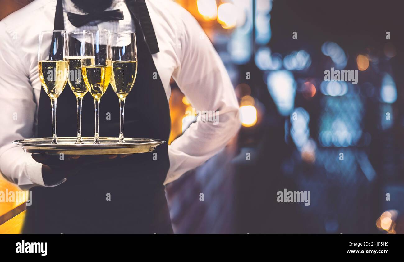 Waiter holding out glasses of sparkling wine at event. Stock Photo