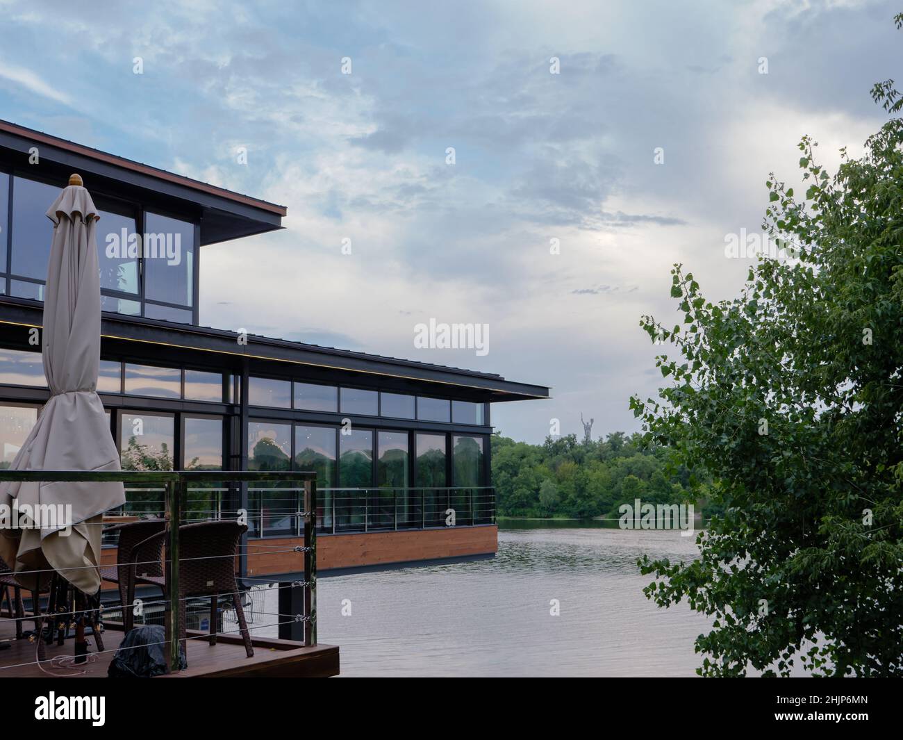 Modern restaurant with an outdoor open terrace with chairs and umbrella at the left bank of the Dnipro river with a panoramic view over the right bank Stock Photo