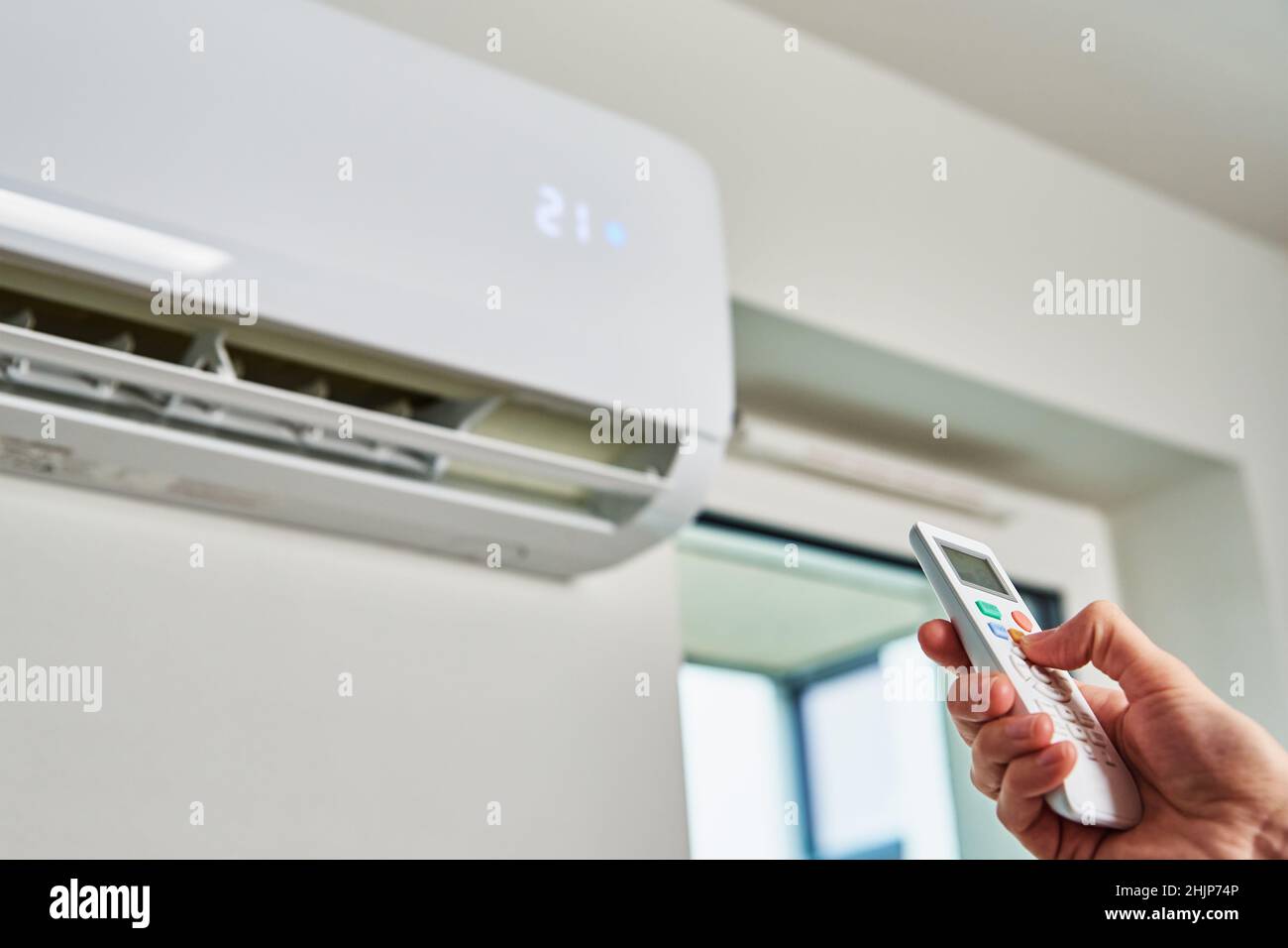 Hand adjusting temperature on air conditioner with remote control, Working air conditioner for