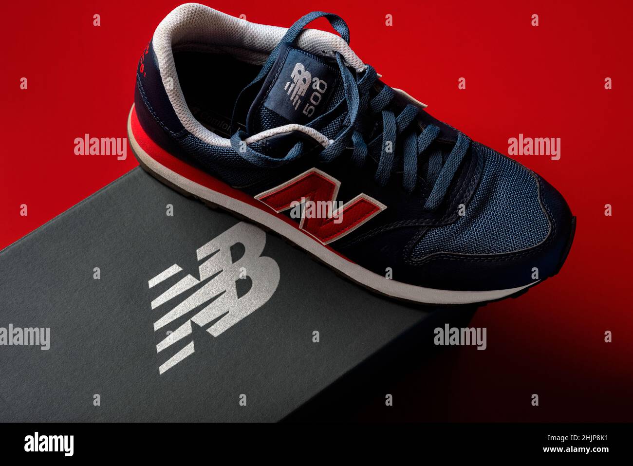 New Balance 500 dark blue sneakers with the New Balance gray box over red background. Casual sport shoes closeup Stock Photo