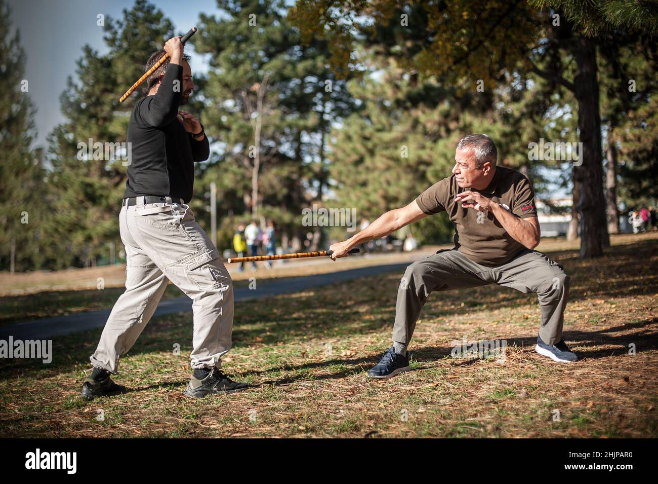 Escrima and kapap instructor demonstrates sticks fighting techniques and training methods in public park. Filipino Martial Arts. Eskrima. Kali Stock Photo