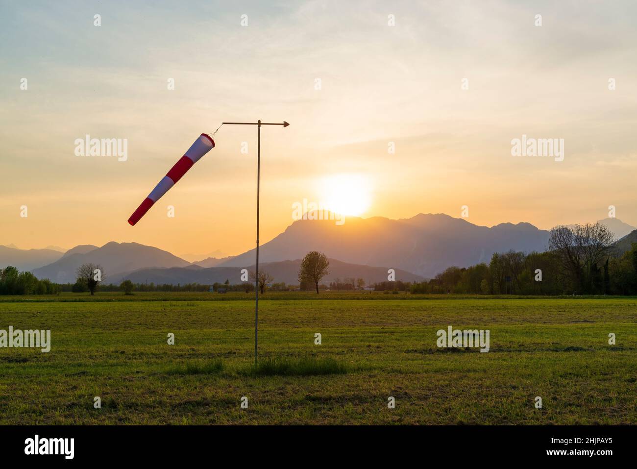 Windsock pole on the small airfield in the mountains. Sunset at the airfield. Stock Photo