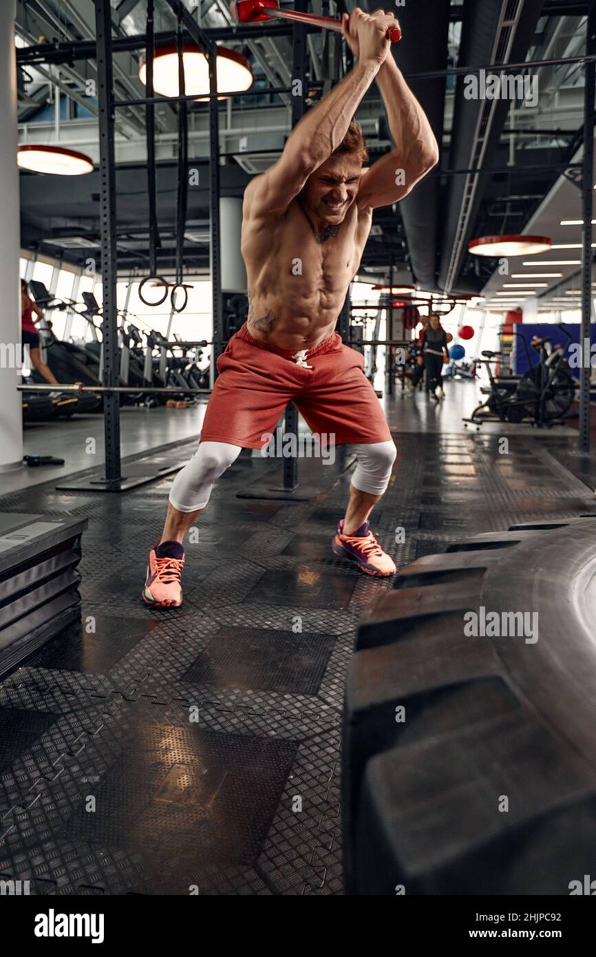 Man fitness training with large and heavy tire hits hammer. Concept workout cross strength Stock Photo Alamy