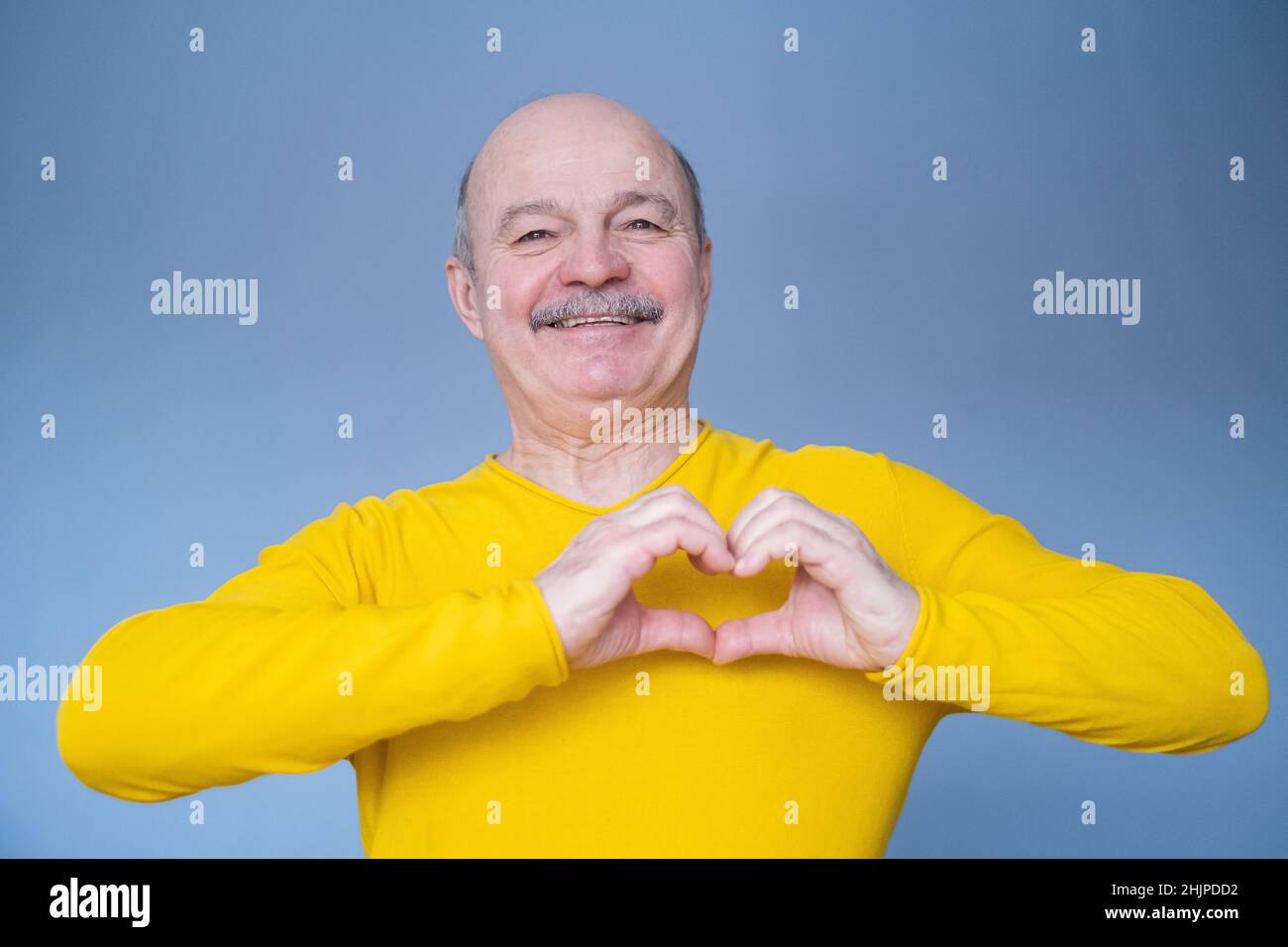 Senior man with smile showing heart symbol with his hands. Health concept. Stock Photo