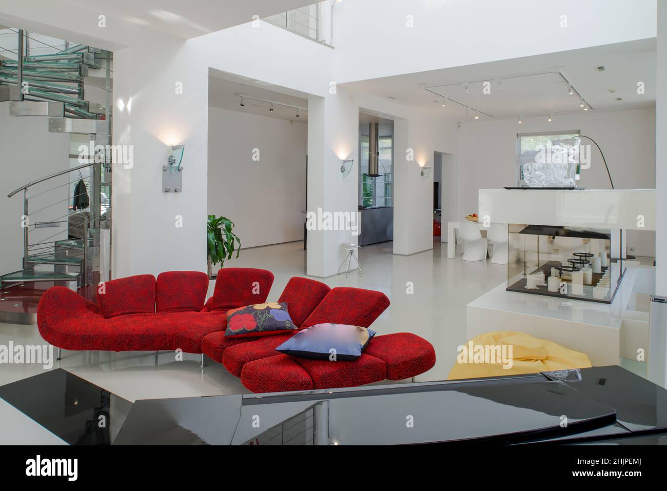 Modern interior of luxury private house. Spacious living room with red  sofa, white table. Metal and glass spiral staircase Stock Photo - Alamy