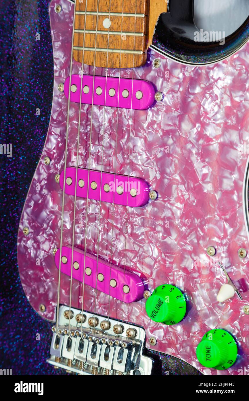 Fender Stratocaster electric guitar in funky purple metalflake paint with neon green controls and purple pearl scratchplate. Stock Photo