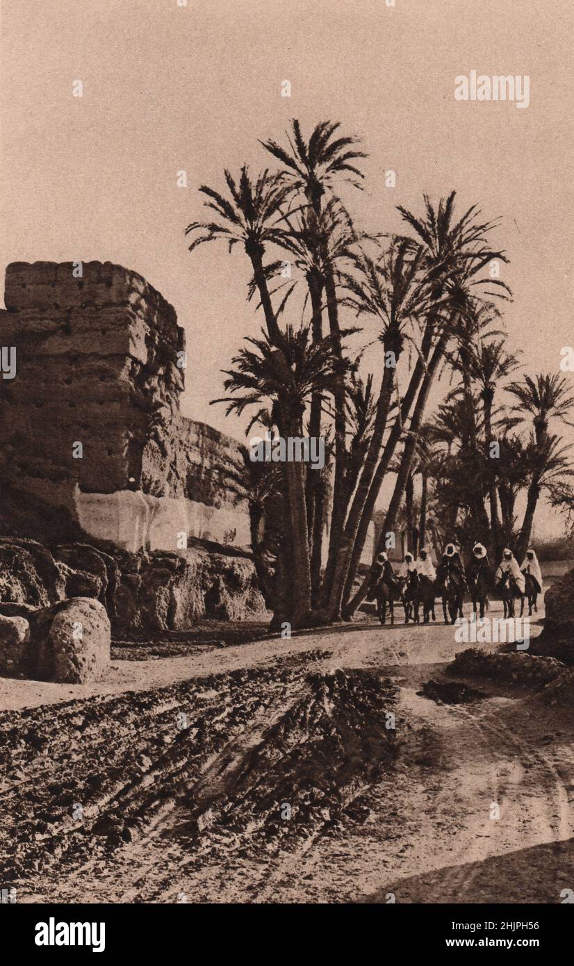 Barbary States. Sadly dinted and riven are the stout old red walls thirty feet high and reinforced by towers, that encompass Marrakesh. Morocco (1923) Stock Photo