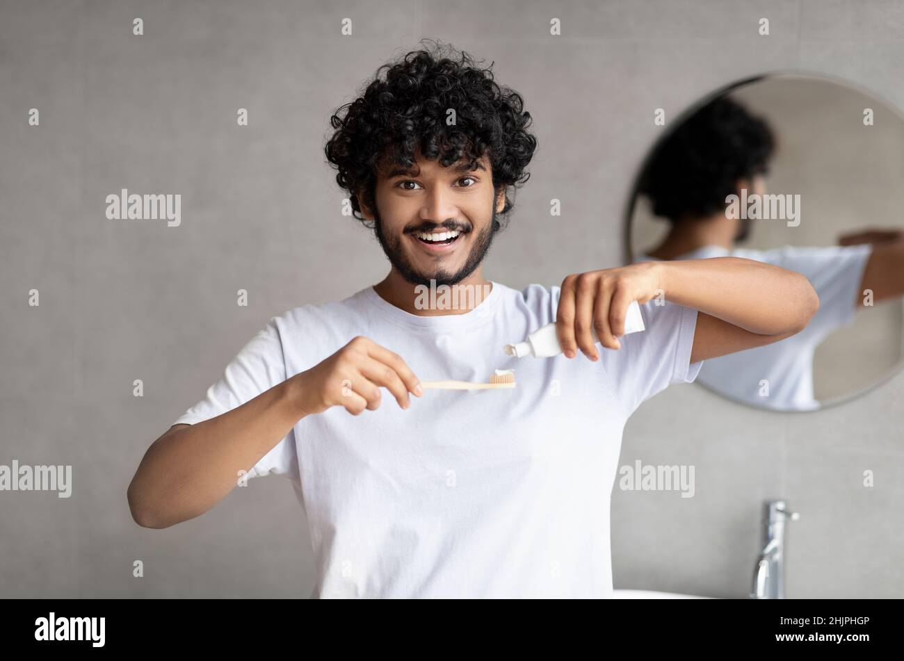 Teeth cleaning concept. Young indian man applying toothpaste on ...