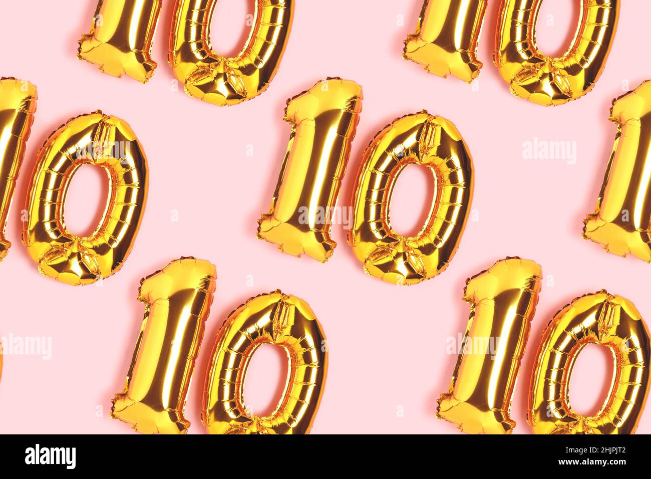 Number 10 golden balloons pattern. Ten years anniversary celebration concept on a pink background. Stock Photo