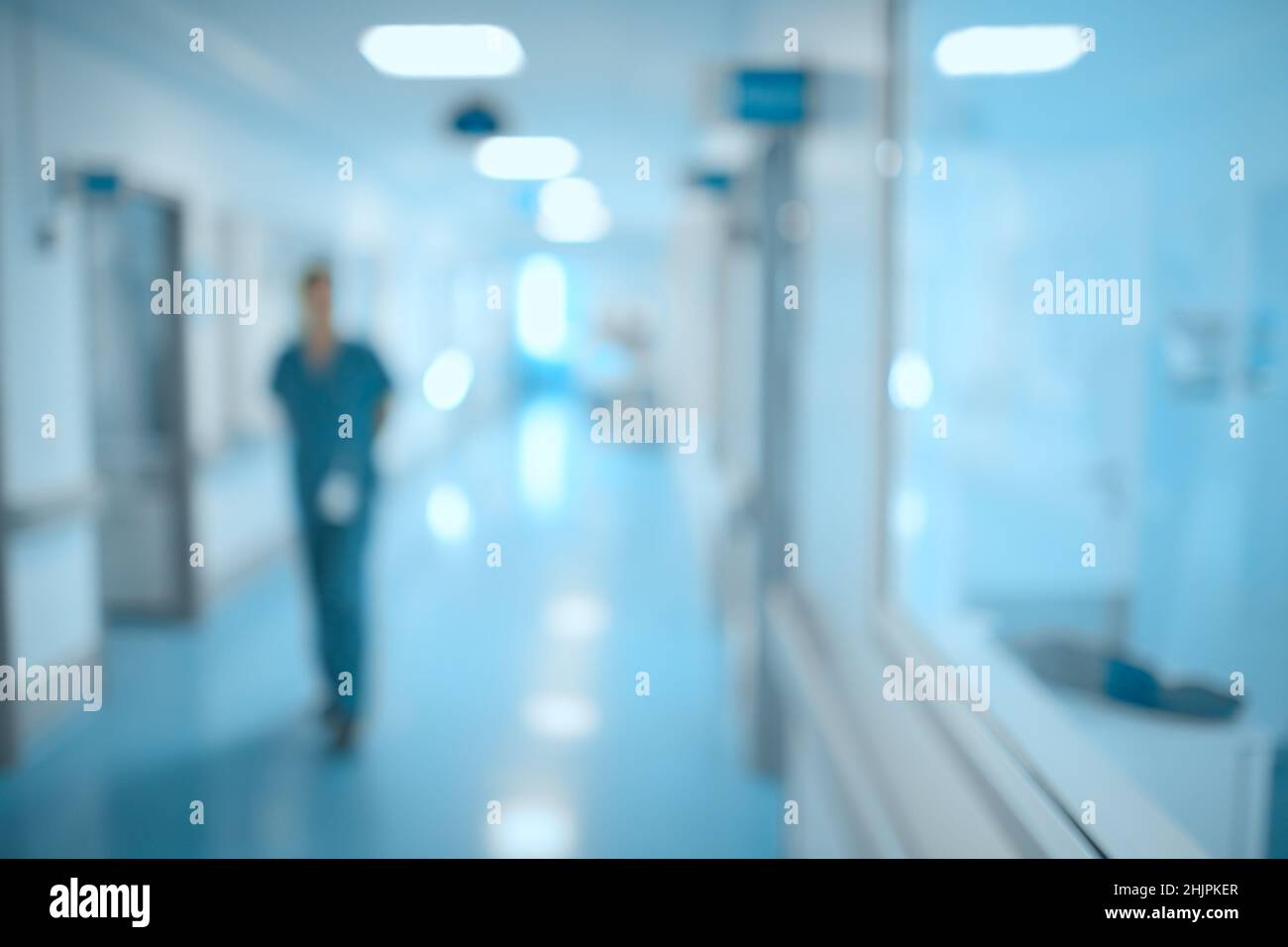 Blurred figure of male doctor walking through the hospoital hall, unfocused background. Stock Photo