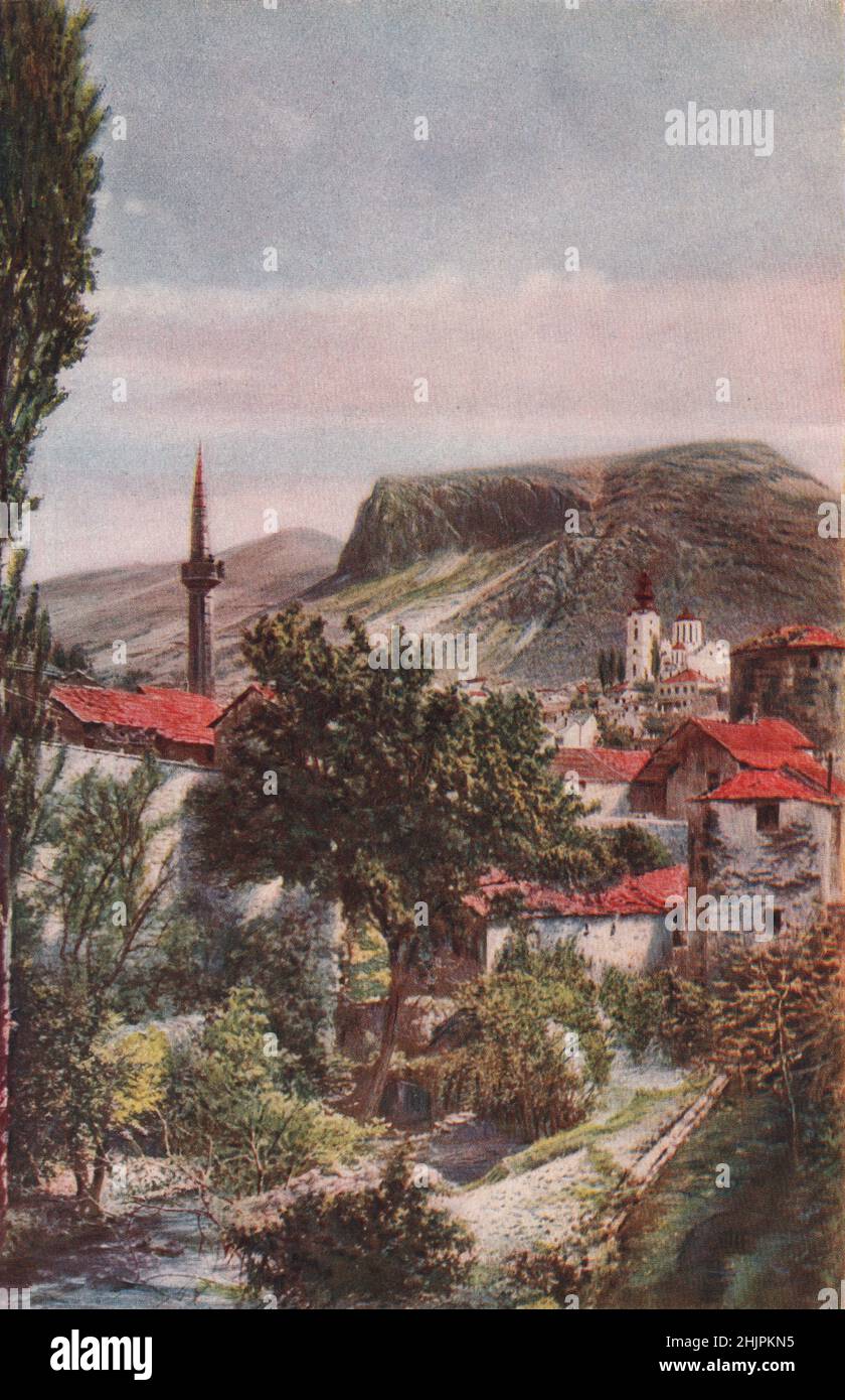 Pencil-Pointed minarets & the noble Greek Cathedral at the foot of the grim hill of Podvelez are salient features of Mostar. Bosnia Herzegovina (1923) Stock Photo