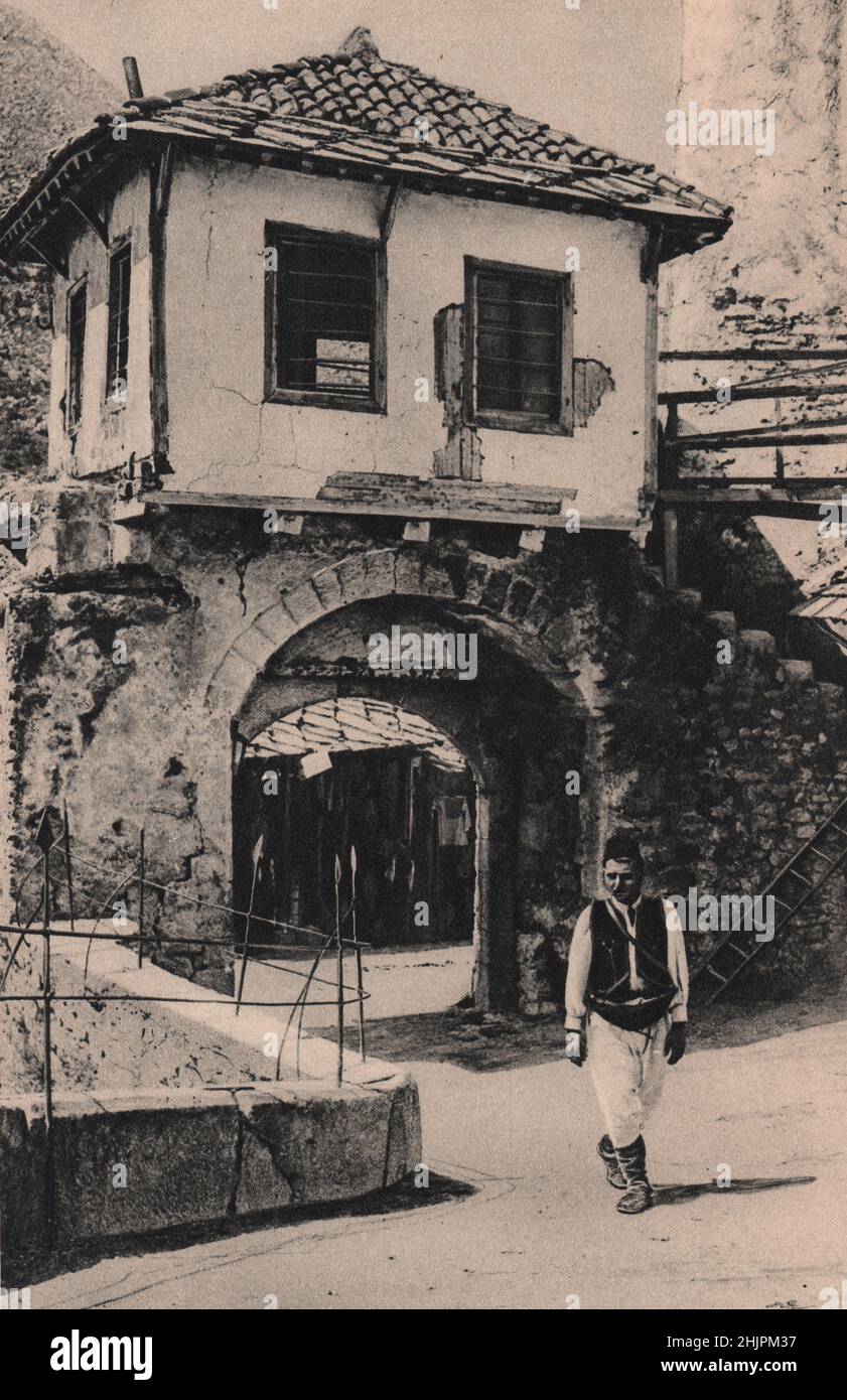 Gate towers guard the approach to the ancient bridge that with its single span of 100 feet crosses the Narenta at Mostar. Bosnia Herzegovina (1923) Stock Photo