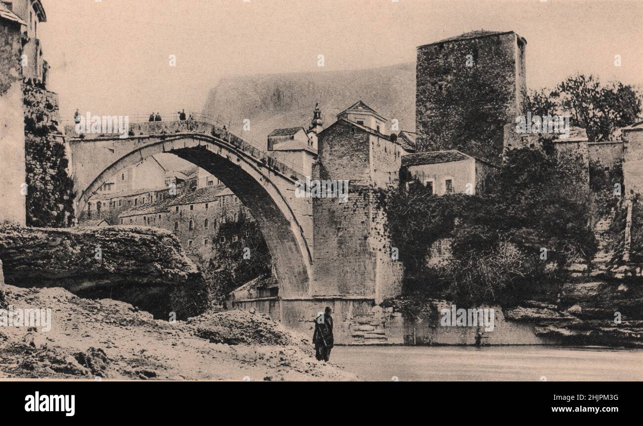 Mostar ,takes its name from this 15th century stone arch that spans the Narenta at a height of sixty feet. Bosnia Herzegovina (1923) Stock Photo