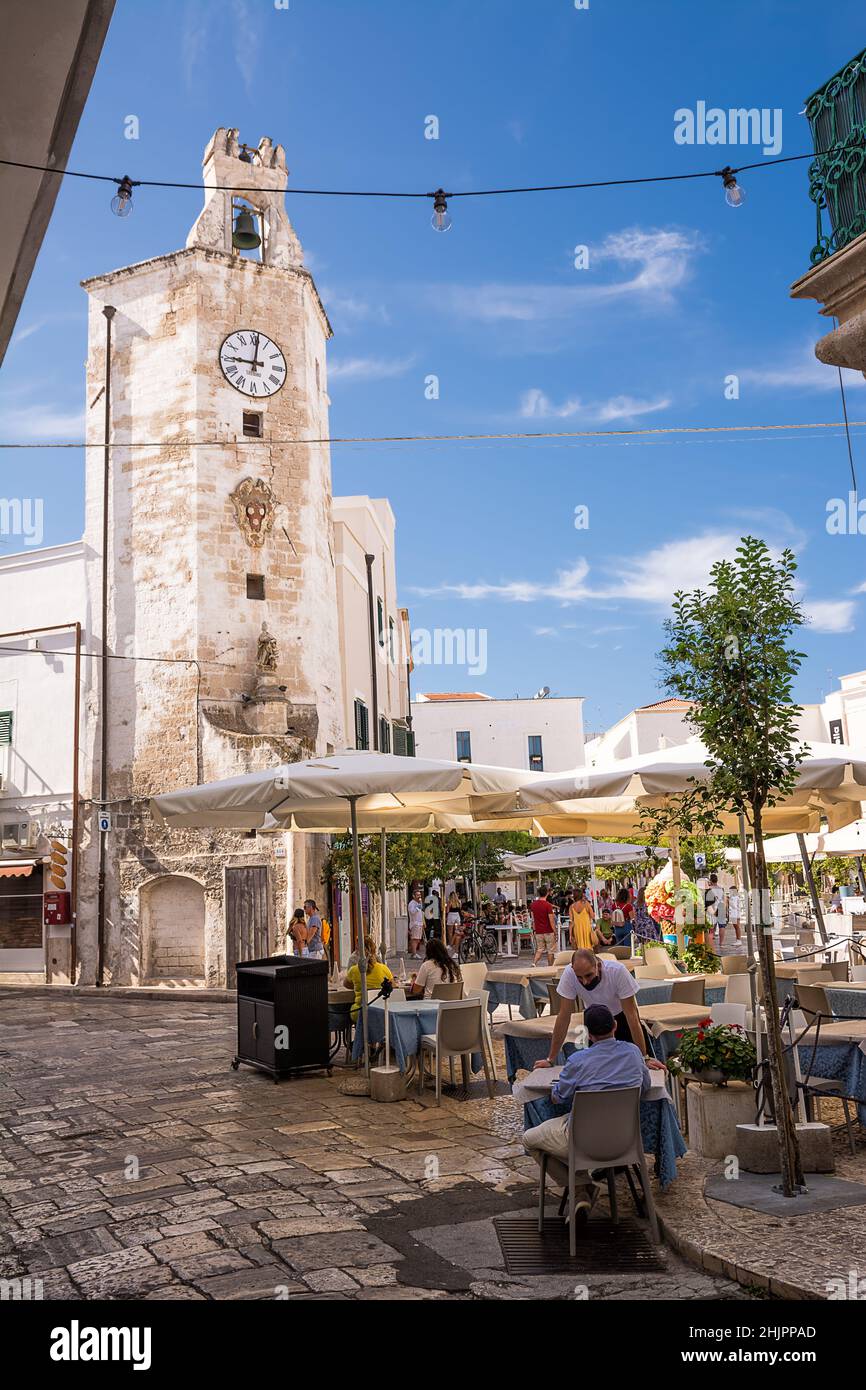 Monopoli, Italy - 20 August 2021: Characteristic square and tower clock with gazebo bar and people tourists in the center of Monopoli (Puglia) Stock Photo