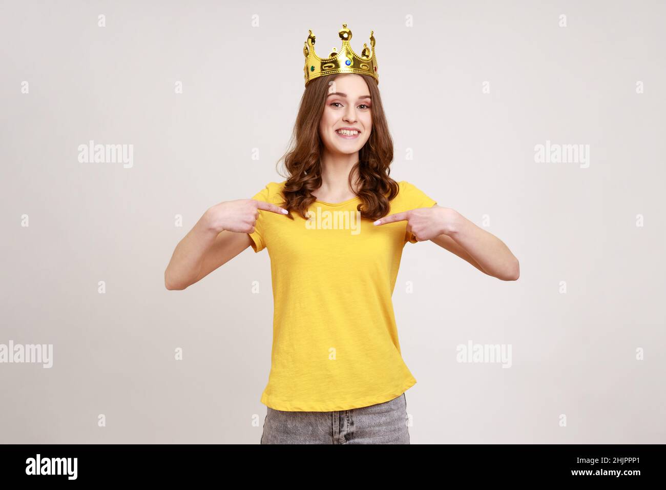 Happy cheerful teenager girl in yellow casual Tshirt and golden crown