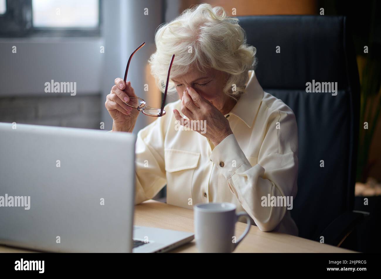 Woman taking off glasses touching her closed eyes Stock Photo