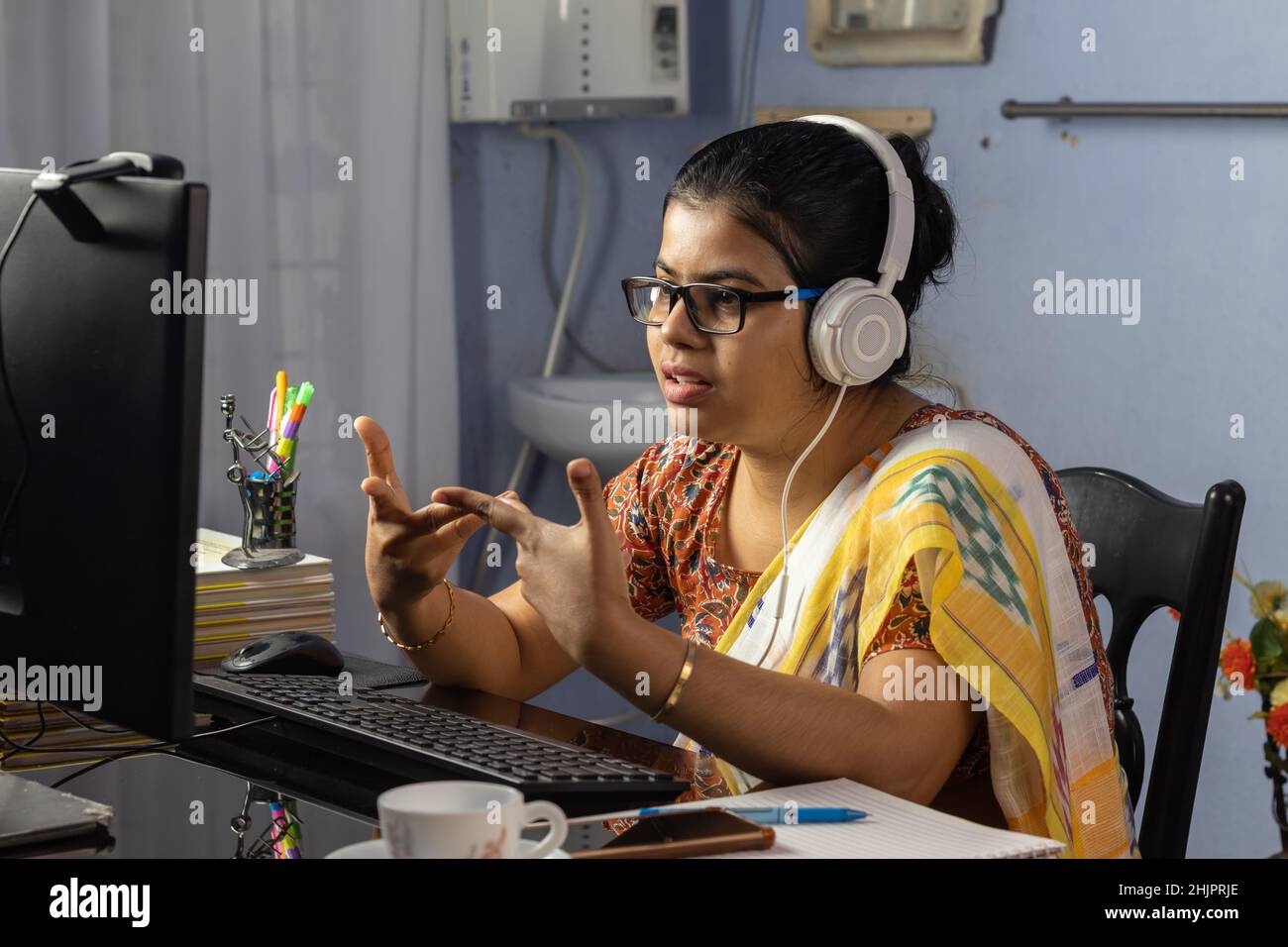 Indian woman in saree working on computer and talking over internet from home, online teaching concept Stock Photo