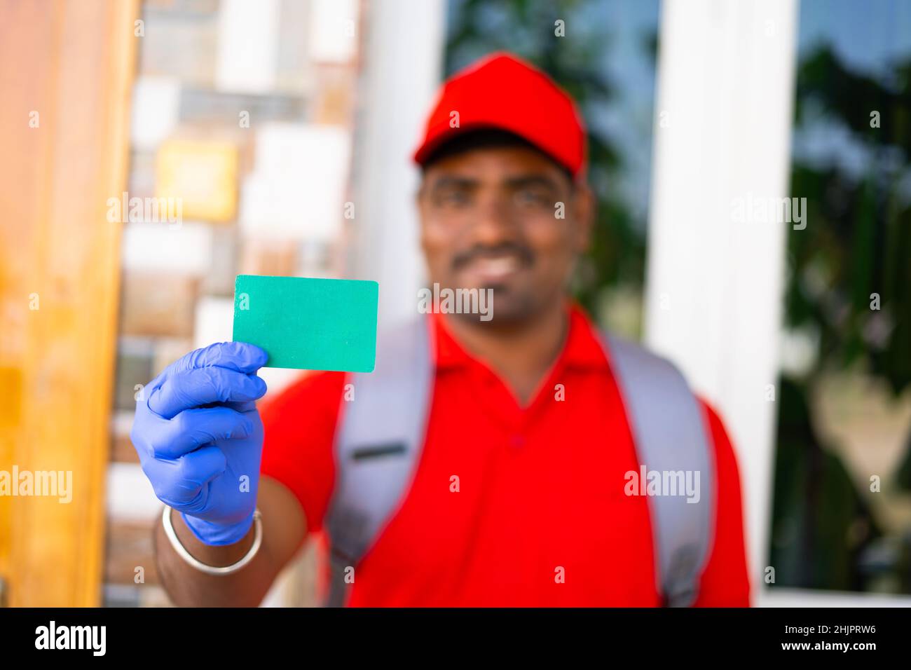 Focus on green card, Young indian delivary boy showing green card by looking at camera - concept home delivary service, job card, advertisment and Stock Photo