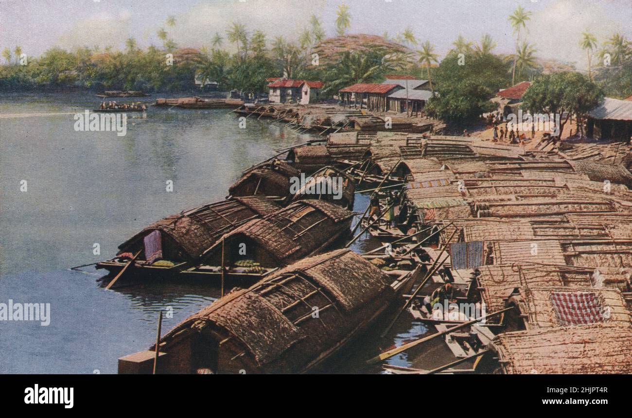 Ceylon River scenery. Punt-like native boats with thatched deck-houses ply upon the rippling waters. Sri Lanka (1923) Stock Photo