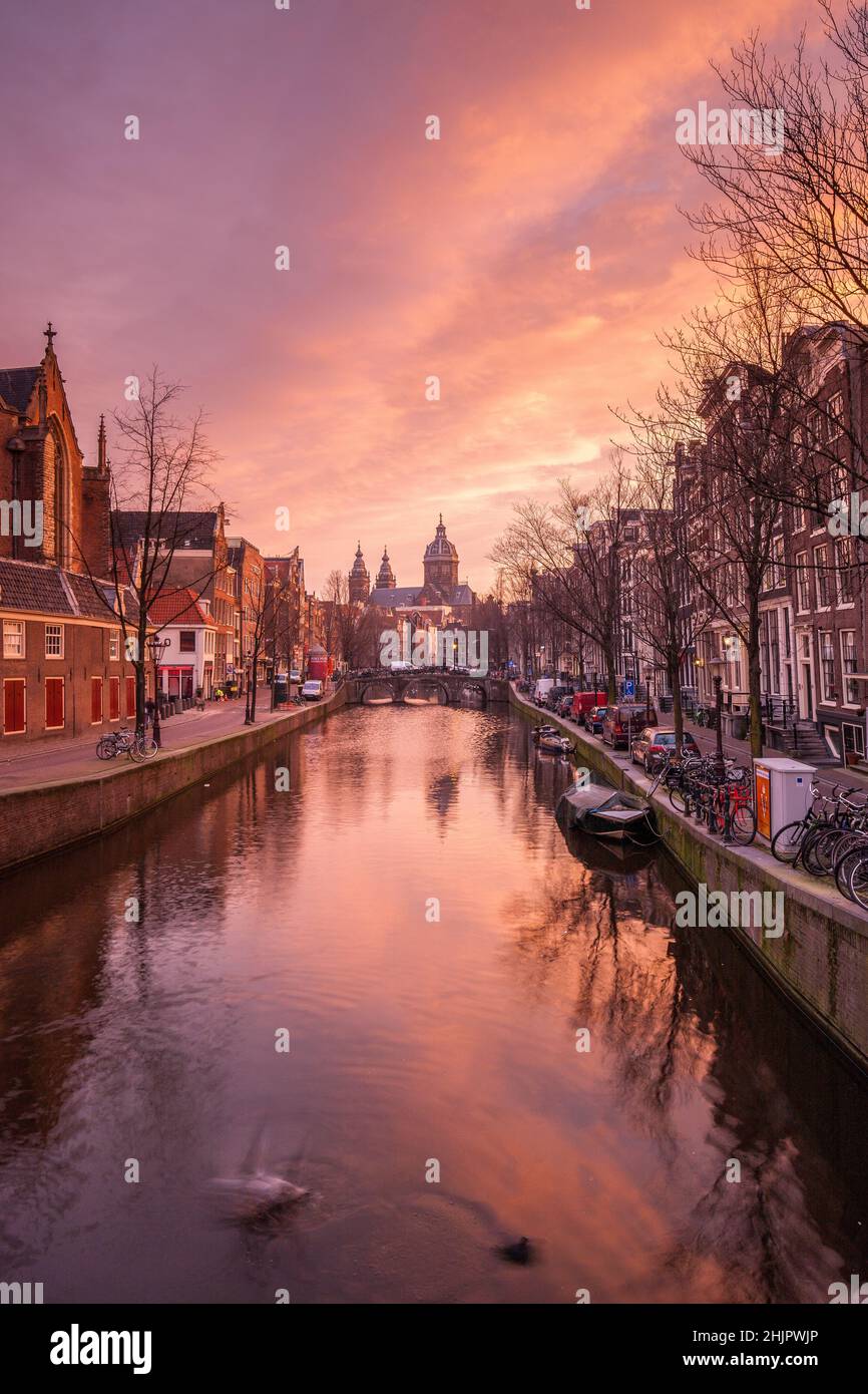 St Nicolas church and bridge with view of an Amsterdam canal at sunrise with canal boats and bicycles Amsterdam Holland Stock Photo
