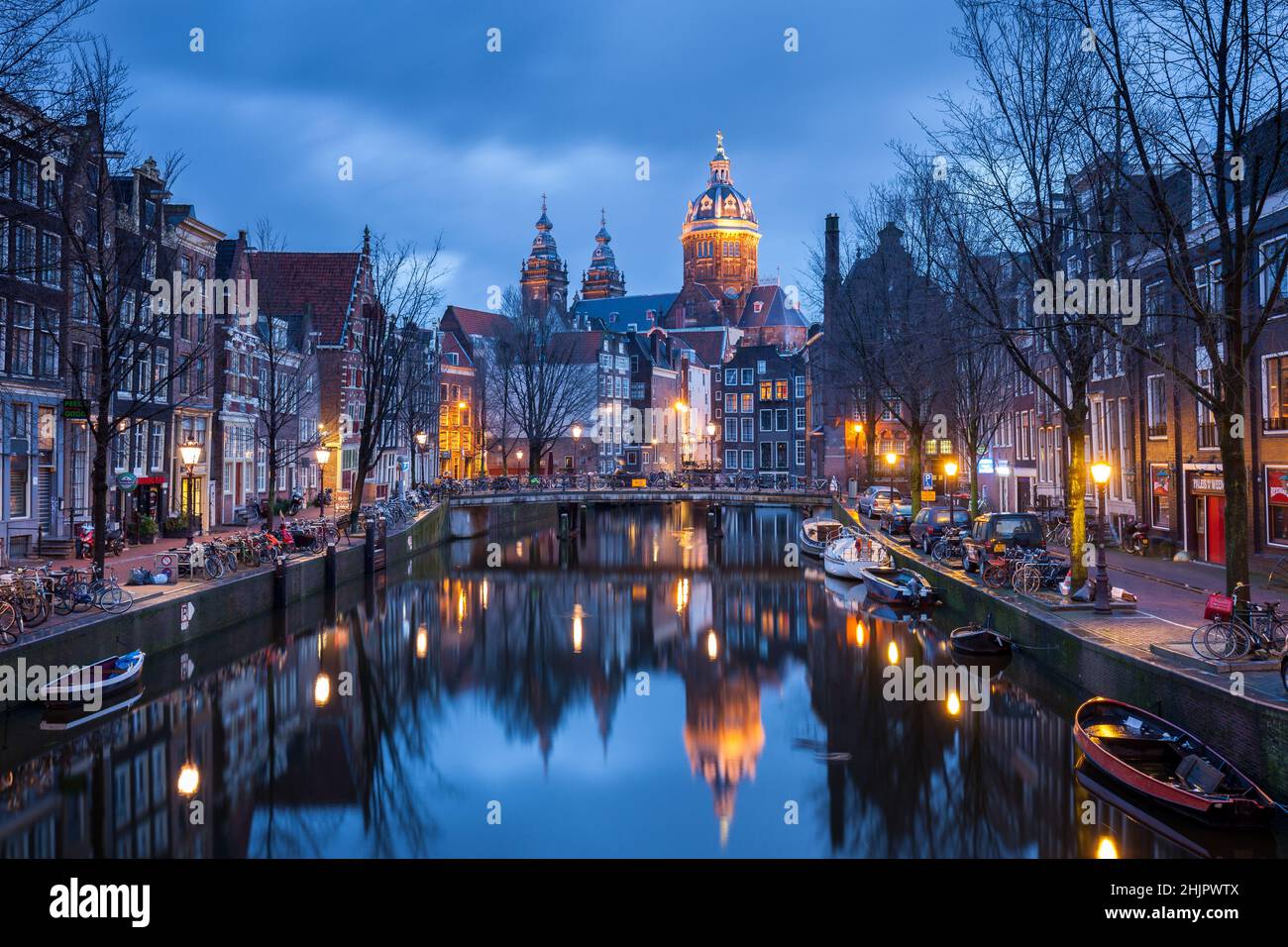 St Nicolas church and bridge with view of an Amsterdam canal at sunrise with canal boats and bicycles Amsterdam Holland Stock Photo