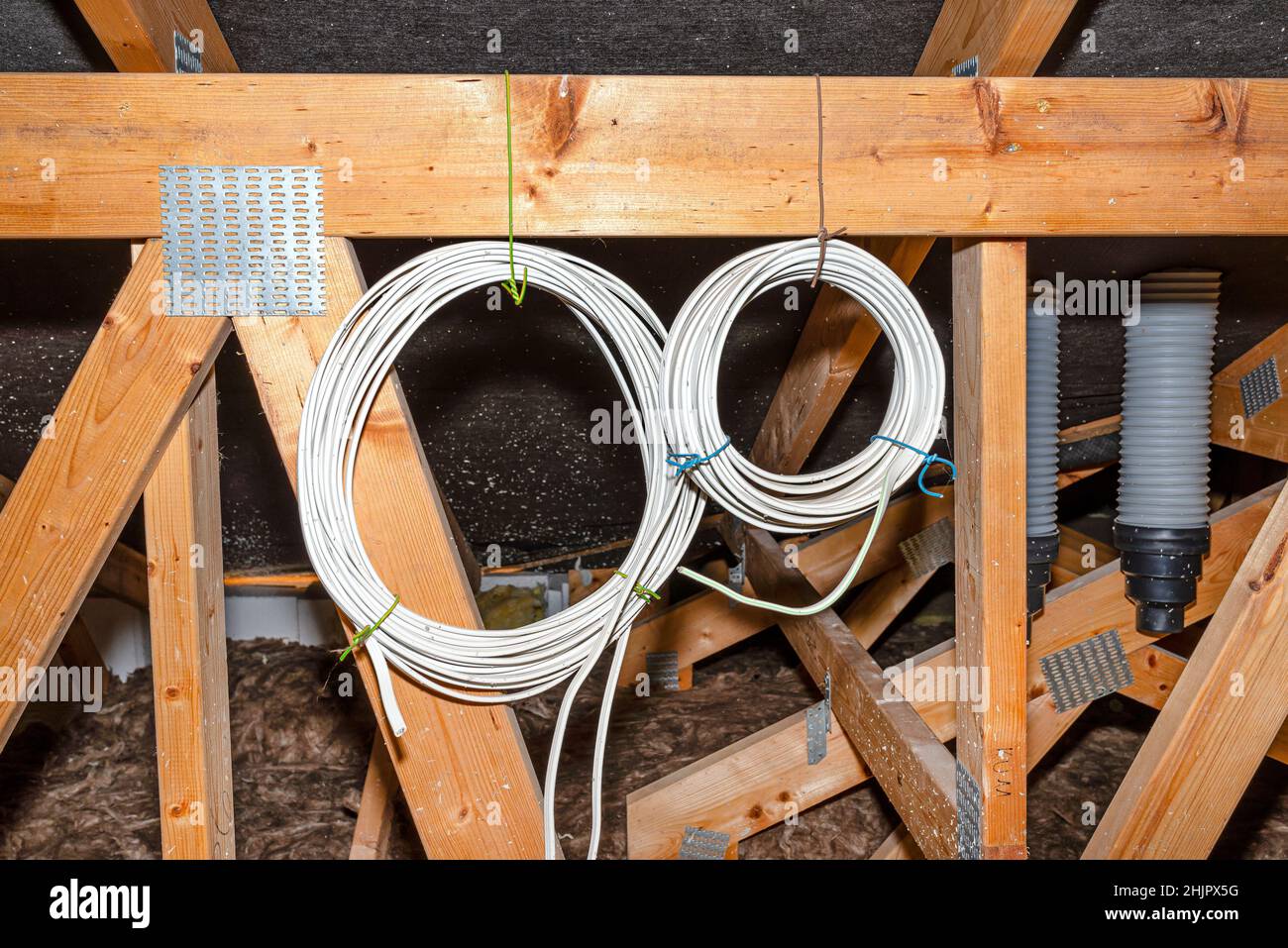Two coils of electric cable hanging from the roof trusses in the attic