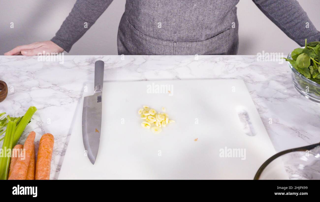 Curring vegetables on a white cutting board to cook vegetarian white bean soup. Stock Photo