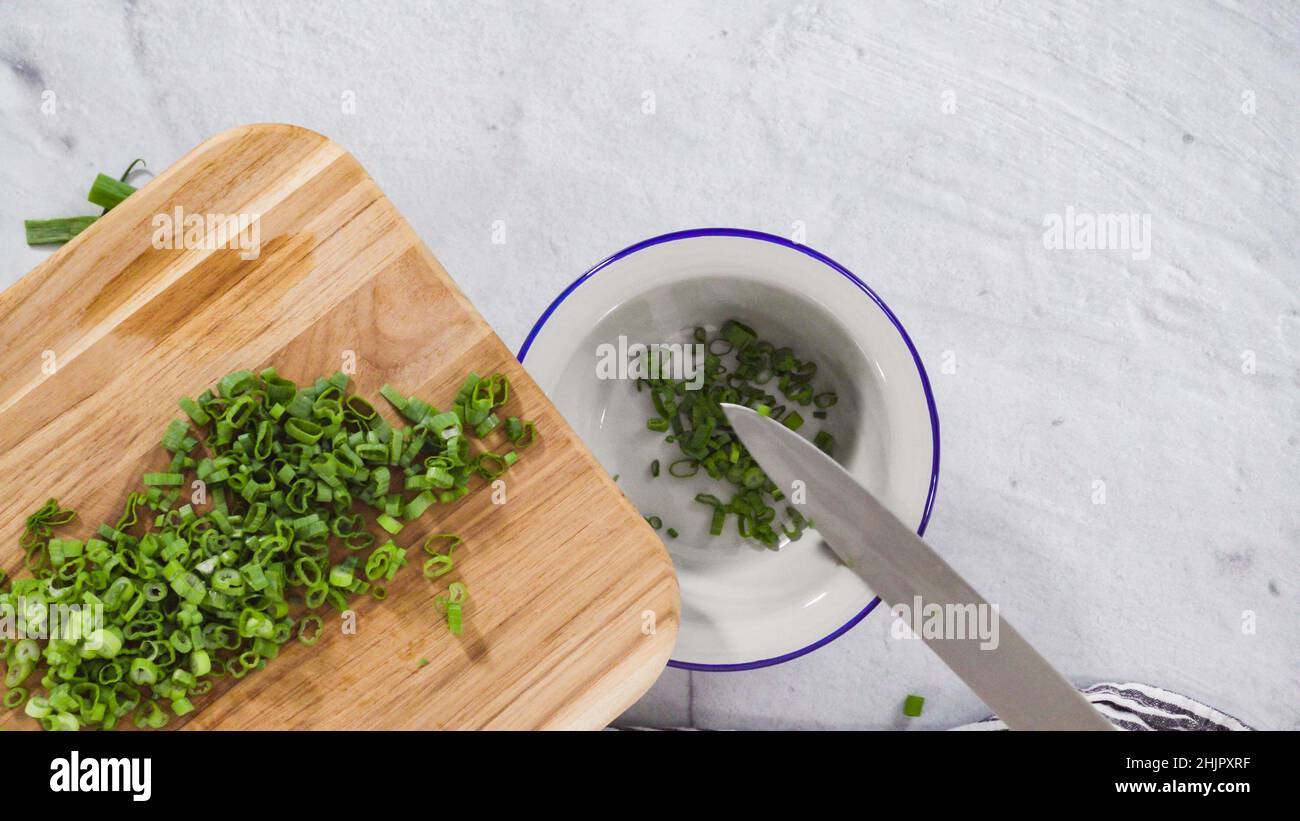 Flat lay. Step by step. Chopping organic green onions on a wood cutting ...