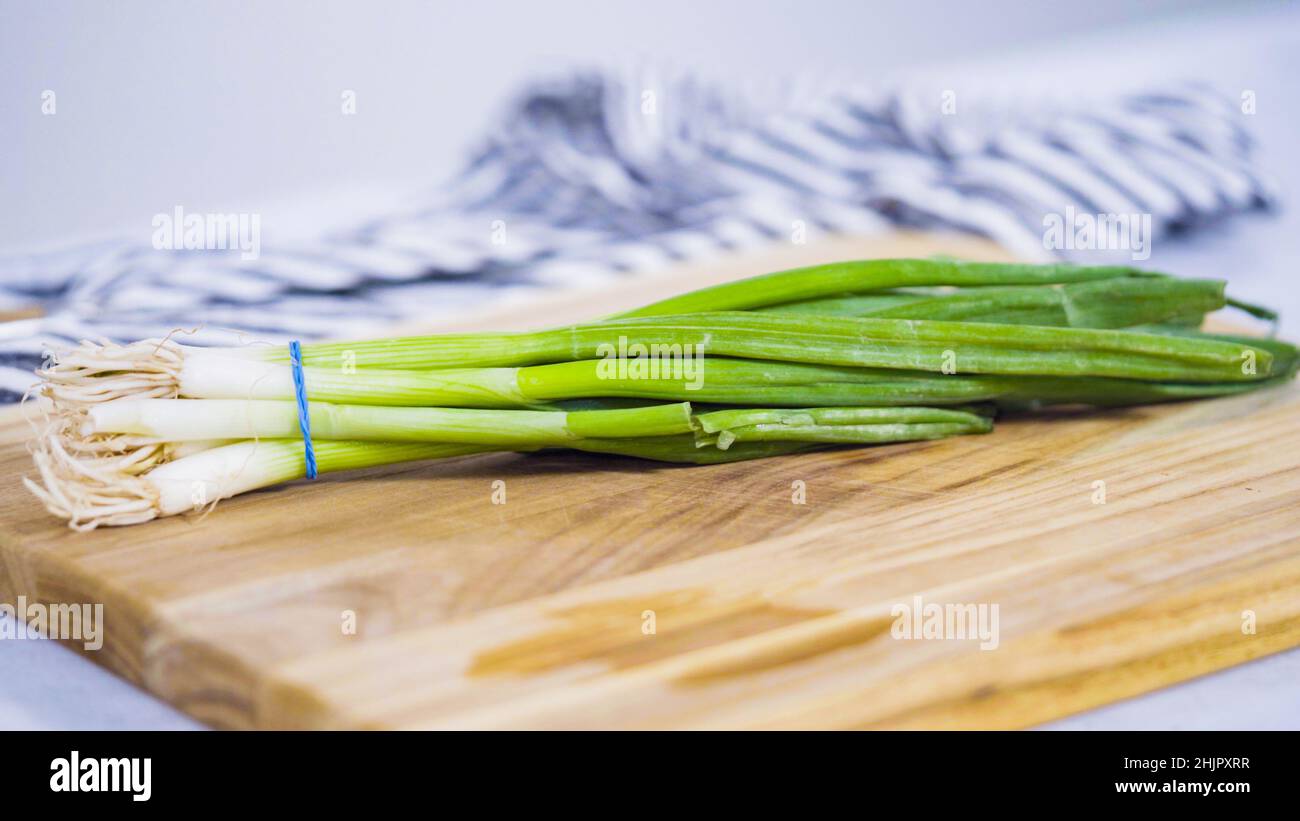 Step by step. Chopping organic green onions on a wood cutting board ...