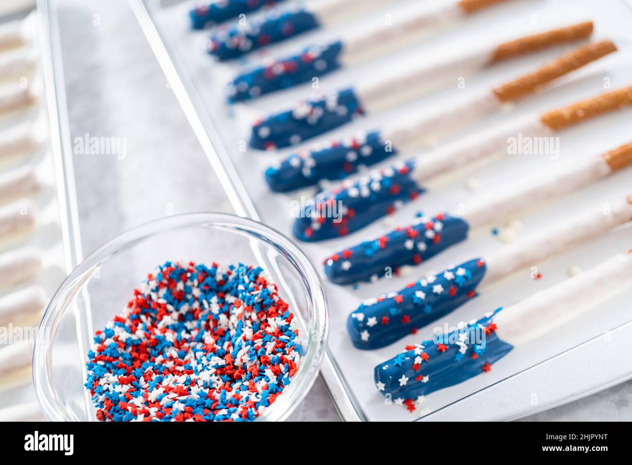 Dipping pretzel rods into the melted chocolate to prepare chocolate ...