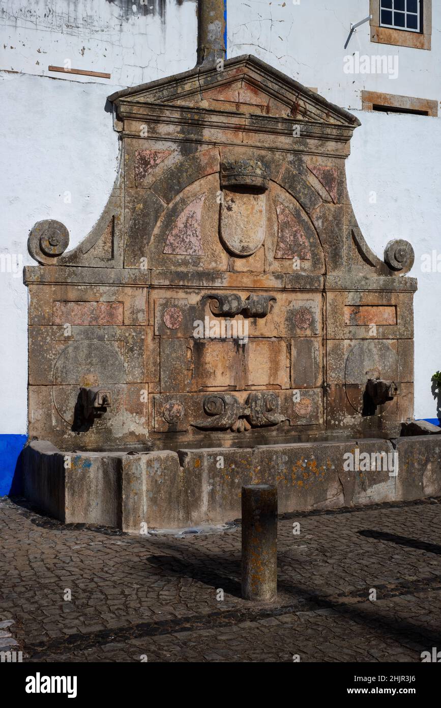 Public drinking fountain, commissioned in 1575 by Queen Catherine of Austria, in the central square of Óbidos, Portugal Stock Photo