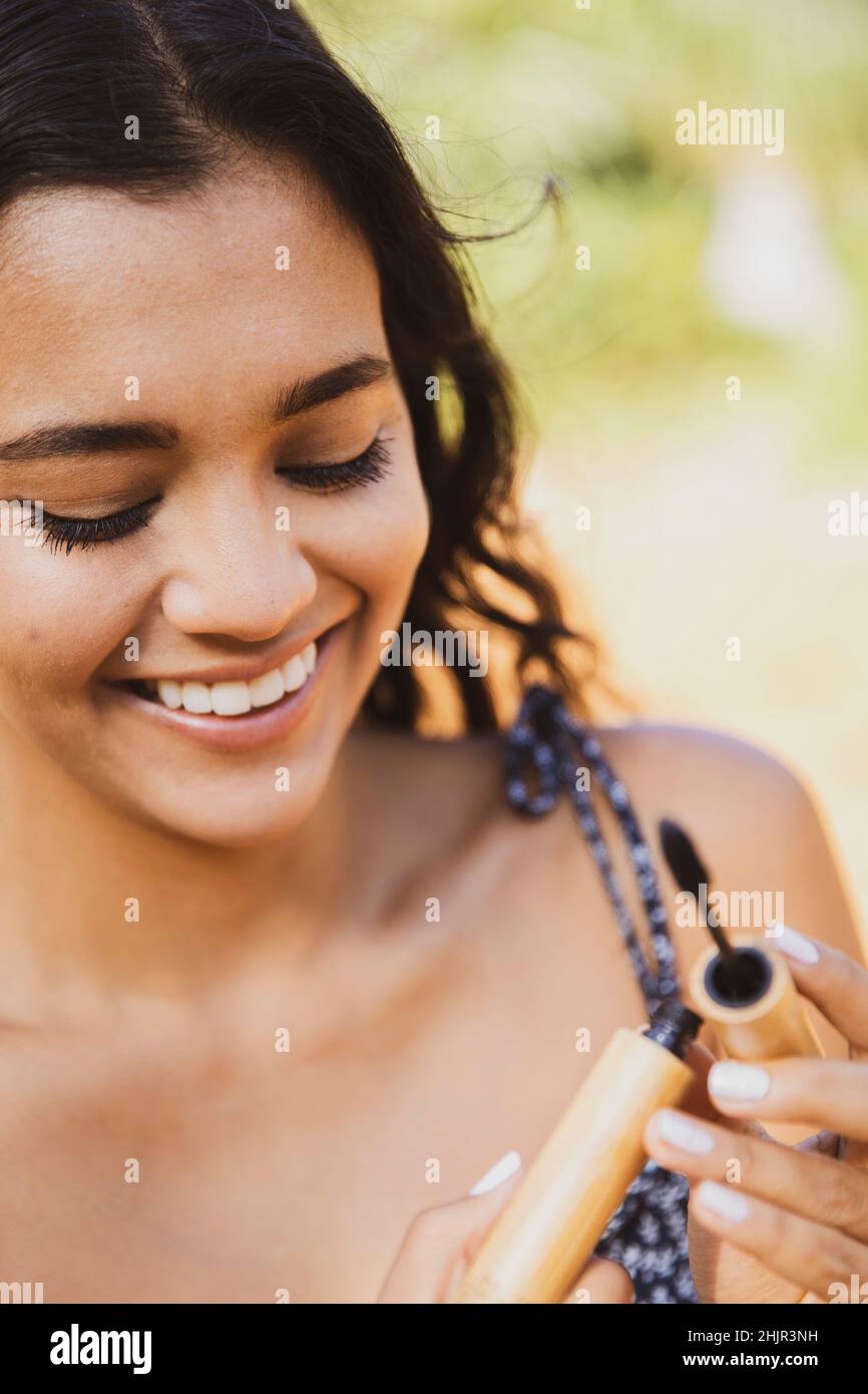 A smiling female opens mascara applicator to apply it Stock Photo