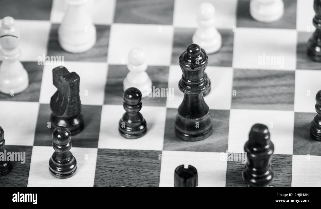 Black and white chess board with Queen in focus, surrounded by pawns, knight and bishop Stock Photo