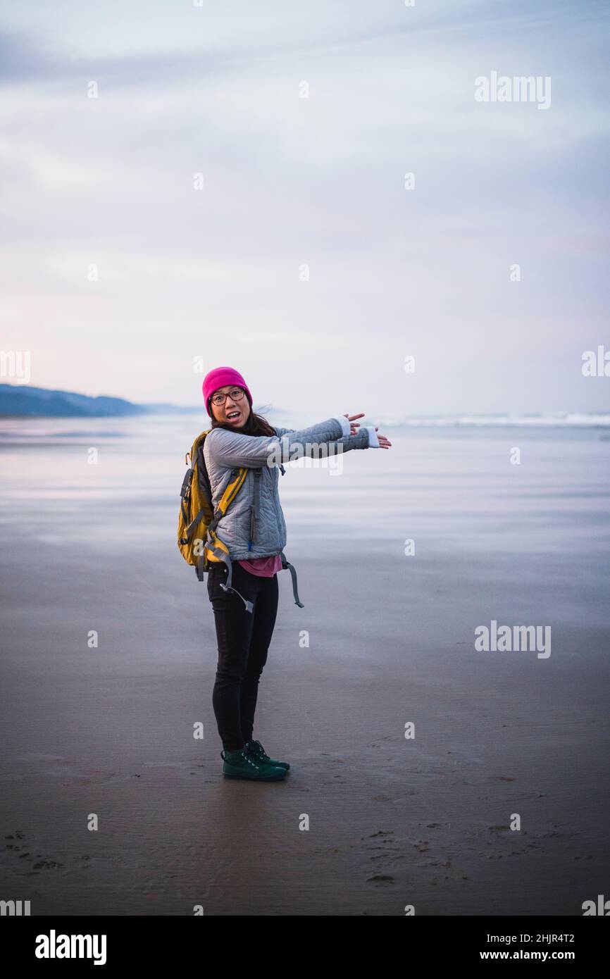 Solo Female Traveler in awe on Oregon beach at sunrise Stock Photo