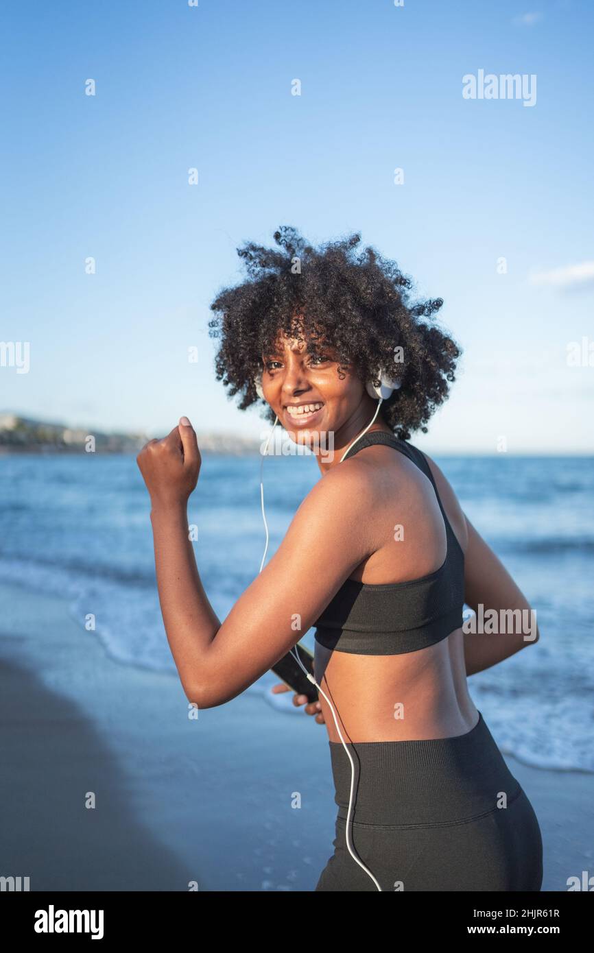 black woman laughing and having fun listening to music on the beach Stock Photo