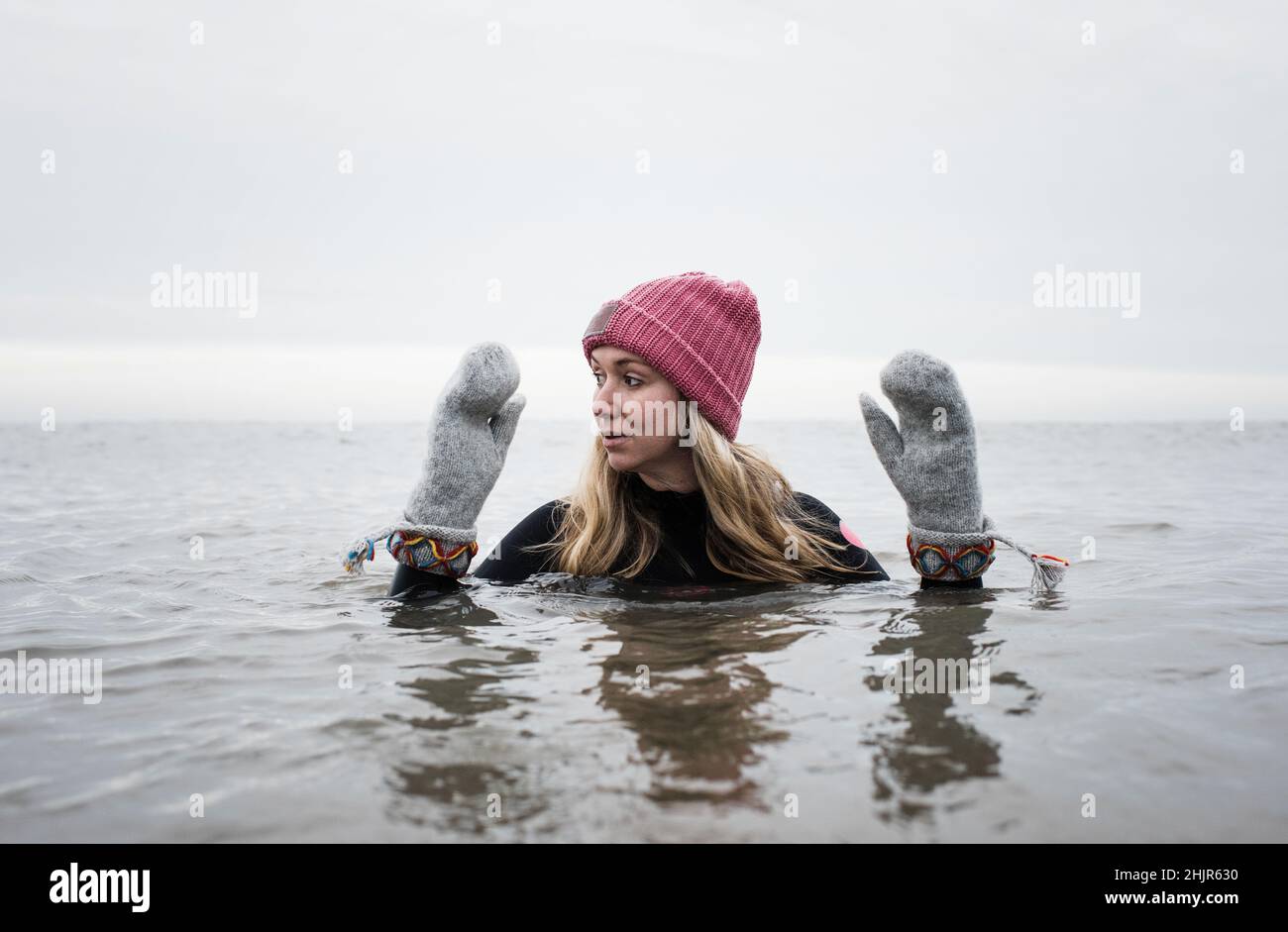 woman breathing cold water swimming with gloves and hat in the ocean