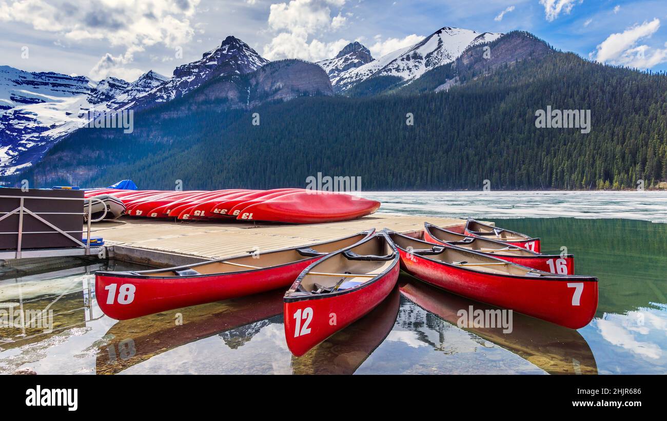 Rote Kajaks auf dem mit einer dünnen Eisschicht überzogenen Lake Louise Stock Photo