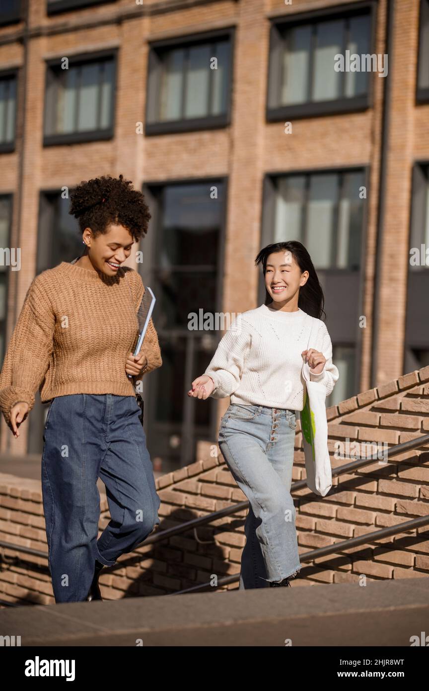 Two girls talking walking up steps in street Stock Photo Alamy